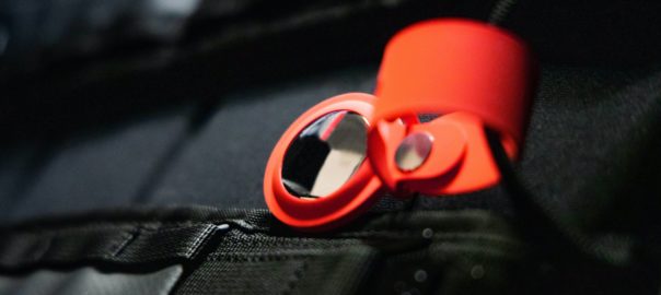 一个苹果机空气装置，围绕着亮橙色带，固定在背包上